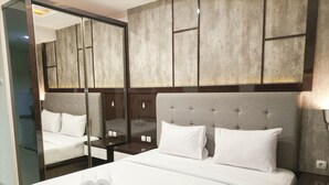 Una habitación de hotel con una cama grande, un espejo y un cabecero de madera.