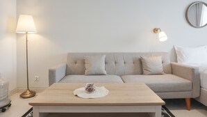 Ein modernes Wohnzimmer mit Sofa, Couchtisch, Lampe und einem Wandspiegel.