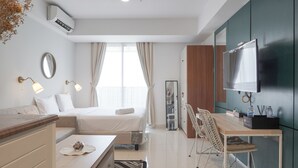 Ein modernes Hotelzimmer mit einem Bett, einem Schreibtisch mit Stuhl, einem Fernseher und einer Minibar.