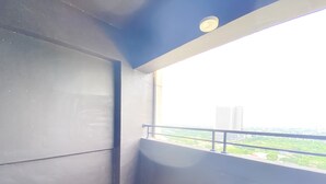 A balcony with a view of a cityscape, including high-rise buildings and greenery. - Fully Furnished And Homey 3Br At Meikarta Apartment (Cikarang)