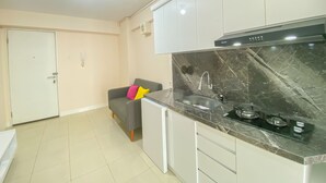 A modern kitchen with white cabinets, a black marble countertop, and a built-in stove. - Minimalist And Good Deal 2Br At Bassura City Apartment (Jakarta)