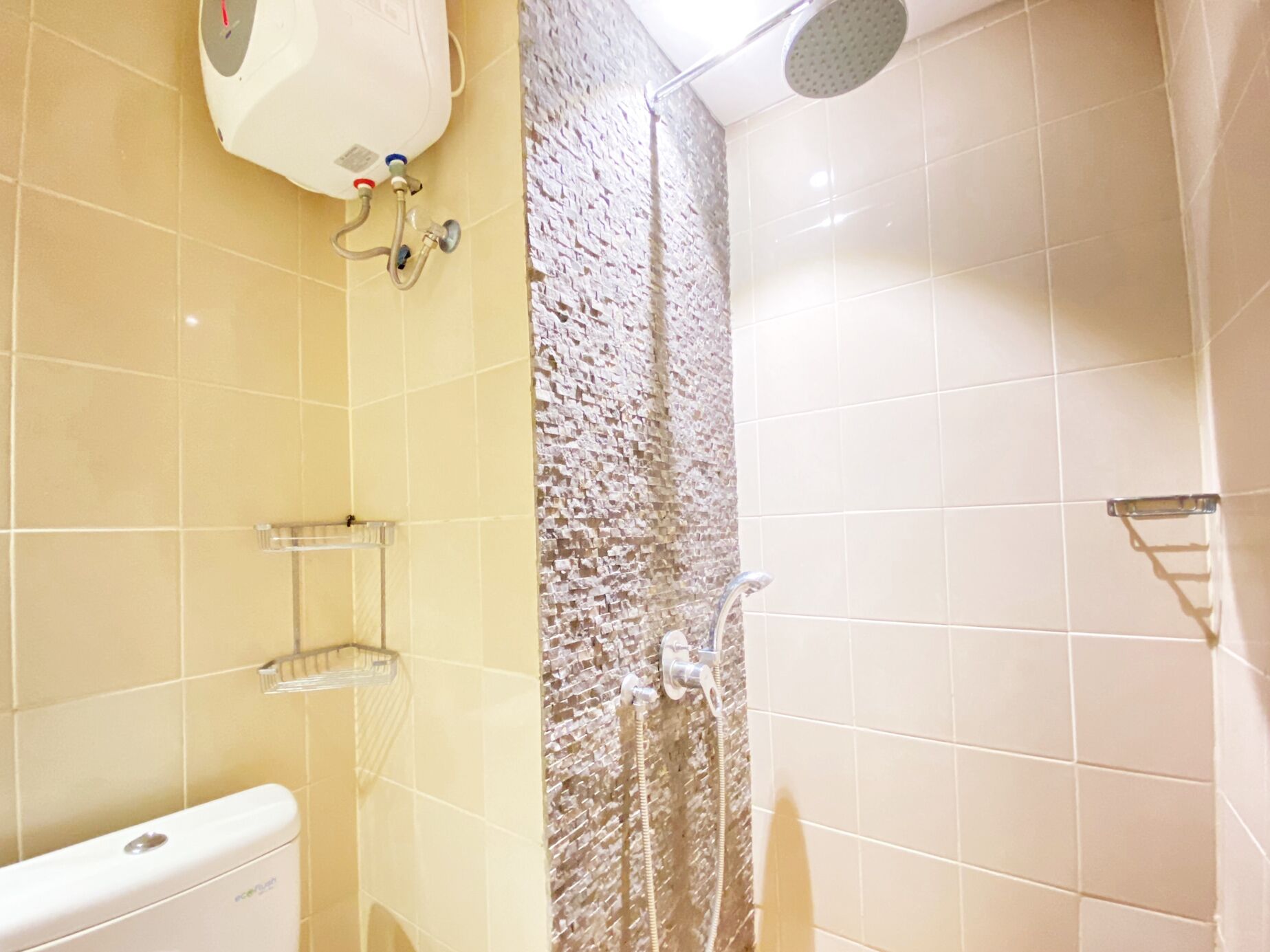 A bathroom with a toilet, a shower with a textured wall, and a ceiling-mounted water heater.