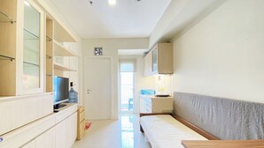 Kompakti hotellihuone, jossa on pieni keittiönurkkaus, sänky, televisio ja kylpyhuone, jossa on suihku.