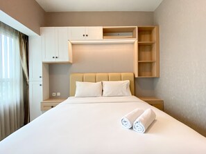 Una habitación de hotel con una cama grande, dos almohadas, cabecero, mesita de noche, armario y una ventana con cortinas.