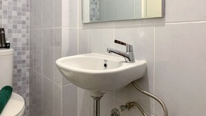 A bathroom with a white sink, chrome faucet, and a mirror above it. - Cozy Studio At Tokyo Riverside Pik 2 Apartment (Teluknaga)