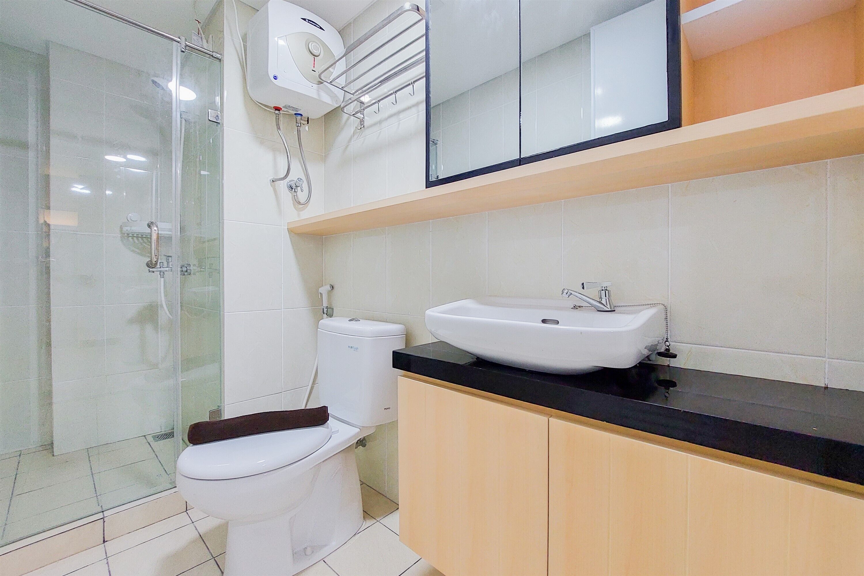 Une salle de bain moderne avec une douche à l’italienne en verre, des toilettes blanches, un lavabo avec un plan-vasque noir et des meubles en bois.