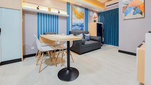 A modern living room with a dining area, a grey sofa, a round table, and a large abstract painting on the wall. - Scenic And Comfortable 2Br Apartment M-Town Residence (Gading Serpong)