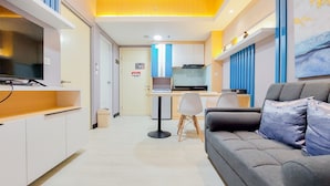 A modern kitchen with a dining area, a sofa, and a TV. - Scenic And Comfortable 2Br Apartment M-Town Residence (Gading Serpong)