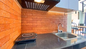 A kitchen with a brick backsplash, a built-in stove, and a sink. - Nice 2Br At Gateway Pasteur Apartment (Cimahi)