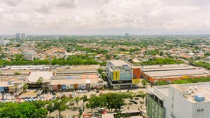 A cityscape with a prominent building labeled "Courts" featuring a modern design with a flat roof and a mix of commercial and residential buildings in the background. - Good Deal And Simply Look Studio Room At Transpark Bintaro Apartment (South Tangerang)