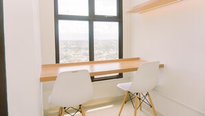 A modern office space with a large window, two white chairs, and a wooden desk. - Good Deal And Simply Look Studio Room At Transpark Bintaro Apartment (South Tangerang)