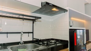 A modern kitchen with a black countertop, stainless steel sink, and a black refrigerator. - Good Deal And Simply Look Studio Room At Transpark Bintaro Apartment (South Tangerang)