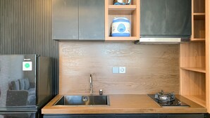 A modern kitchen with a built-in sink, a kettle, a rice cooker, and a stove. - Stylisth 1Br At Tokyo Riverside Pik 2 Apartment (Teluknaga)