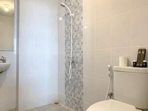 A bathroom with a shower, toilet, sink, and a tiled wall with a mosaic pattern. - Stylisth 1Br At Tokyo Riverside Pik 2 Apartment (Teluknaga)