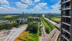 A high-rise building with multiple balconies and a view of a highway and greenery below. - Elegant Studio At Sky House Bsd Apartment Near Aeon Mall (Pagedangan)
