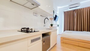 A compact kitchen with a built-in stove, sink, and a small refrigerator. - Elegant Studio At Sky House Bsd Apartment Near Aeon Mall (Pagedangan)
