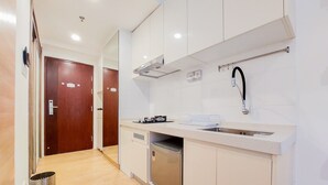 A modern kitchen with white cabinets, a stainless steel dishwasher, and a sink with a faucet. - Elegant Studio At Sky House Bsd Apartment Near Aeon Mall (Pagedangan)