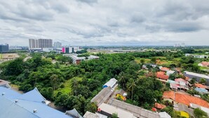 Paisagem urbana com vegetação densa, edifícios residenciais e arranha-céus.