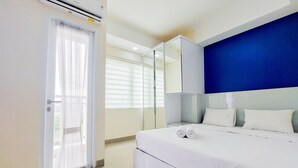 Quarto moderno com cama grande, guarda-roupa e porta de vidro deslizante para área externa.