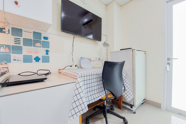 A small office with a desk, chair, and a TV on the wall.
