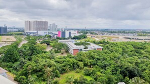 En stadsbild med höga byggnader, ett stort köpcentrum och tät vegetation.
