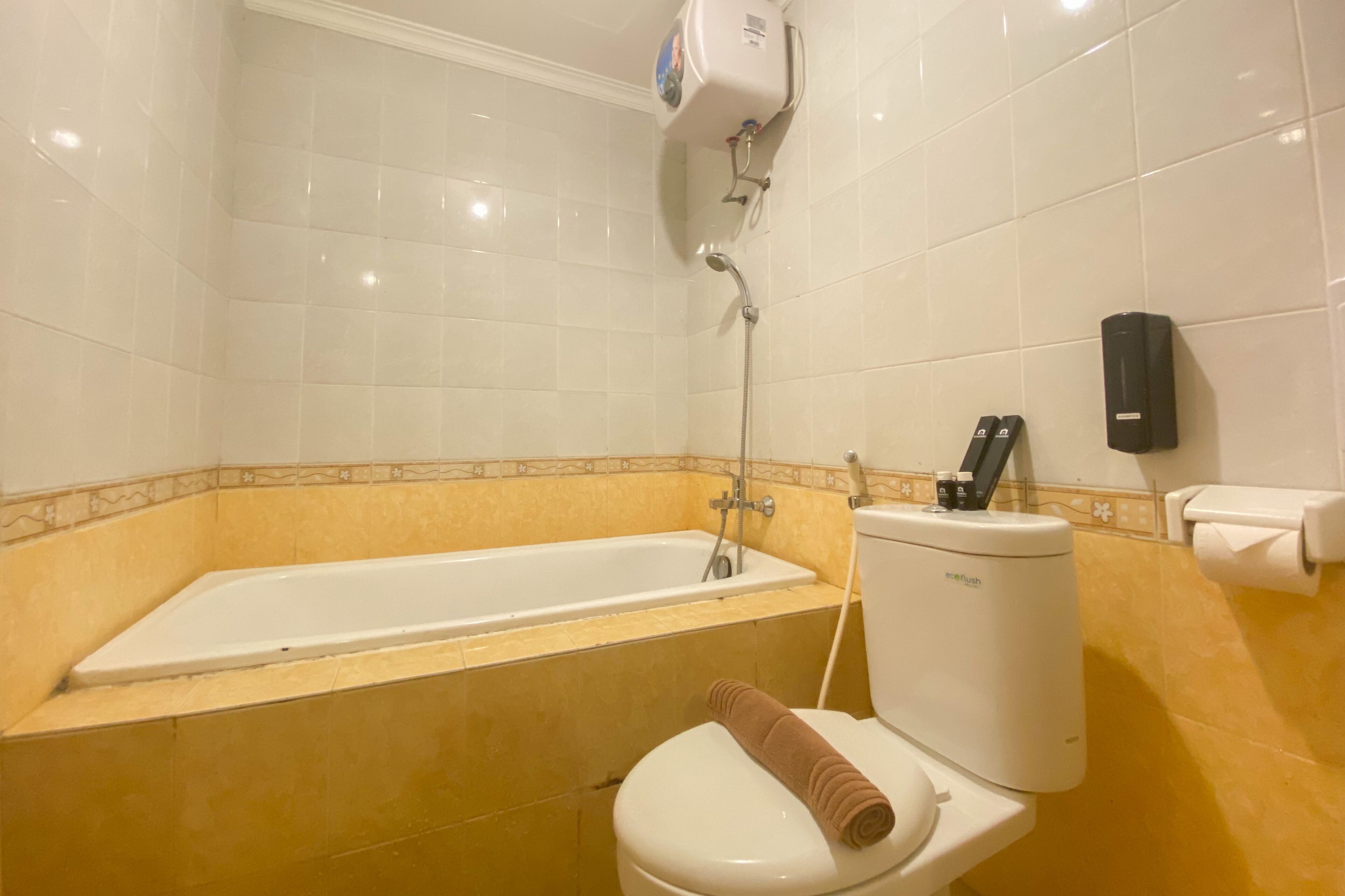 A bathroom with a bathtub, toilet, and a hand dryer.