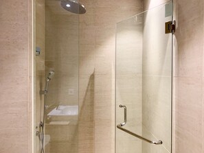 Une douche fermée par des parois en verre, dotée d’un pommeau de douche à main et d’un robinet à main.
