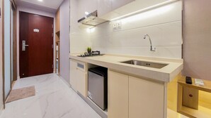 A modern kitchen with a built-in dishwasher, a stainless steel sink, and a compact refrigerator. - Scenic Designed And Comfy Studio At Sky House Bsd Apartment (Pagedangan)