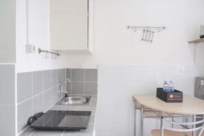A kitchen with a sink, stove, and a small table with a bottle holder.