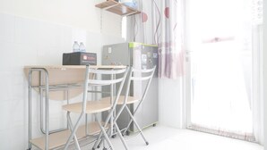 Ein kleines Zimmer mit Küchenzeile, einem Tisch, zwei Stühlen und einem fensterbepflanzten Fenster.