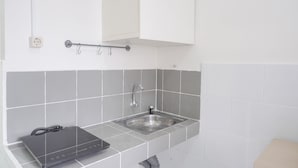 Eine moderne Küche mit Spüle aus Edelstahl, grauer Fliesenrückwand und weißer Arbeitsplatte.