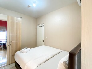 A hotel room with a bed, a wardrobe, a mirror, and a ceiling light.