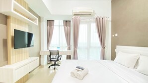 Een hotelkamer met een bed, een bureau met stoel, een televisie en een airconditioner.