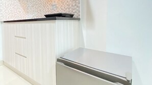 Een moderne keuken met een witte betegelde spatwand, een roestvrijstalen koelkast en een houten kastje met een greep.