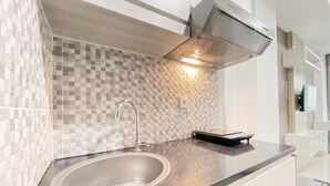Een moderne keuken met een roestvrijstalen spoelbak, een zwart aanrecht en een geruit achterwand.