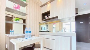 A modern kitchen with a central island, bar stools, and water bottles on the counter. - Chic And Cozy 2Br At Mekarwangi Square Cibaduyut Apartment (Bandung)