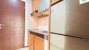 Eine Küche mit Holzausstattung, einem Edelstahlkühlschrank und einer Mikrowelle.
