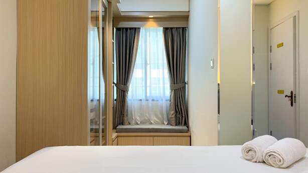 A hotel room with a bed, a window with curtains, a wardrobe, and a door. - Comfort And Enjoy Living 2Br At Daan Mogot City Apartment (Jakarta)
