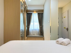 A hotel room with a bed, a window with curtains, a wardrobe, and a door.