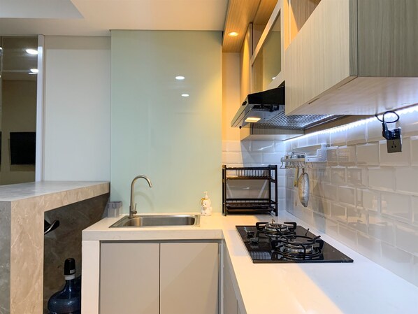 Una cocina moderna con un lavamanos integrado, una estufa a gas y una campana extractora de acero inoxidable.
