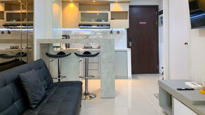 A modern kitchen with a central island, bar stools, and a built-in TV. - Comfort And Enjoy Living 2Br At Daan Mogot City Apartment (Jakarta)