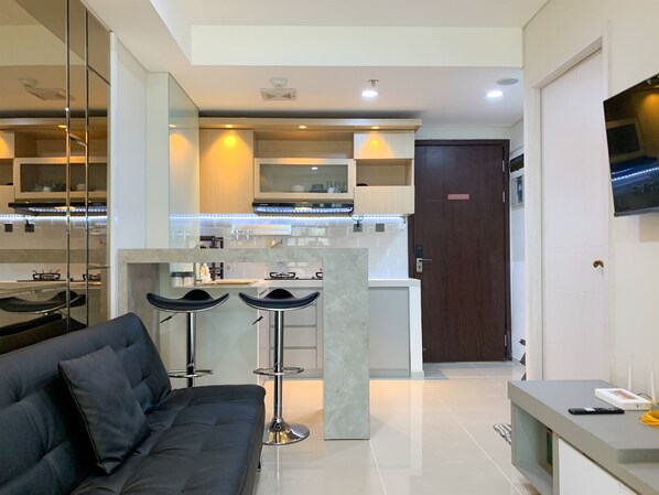 A modern kitchen with a central island, bar stools, and a built-in TV.