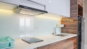Una cocina moderna con armarios blancos, un refrigerador de acero inoxidable y un horno empotrado.