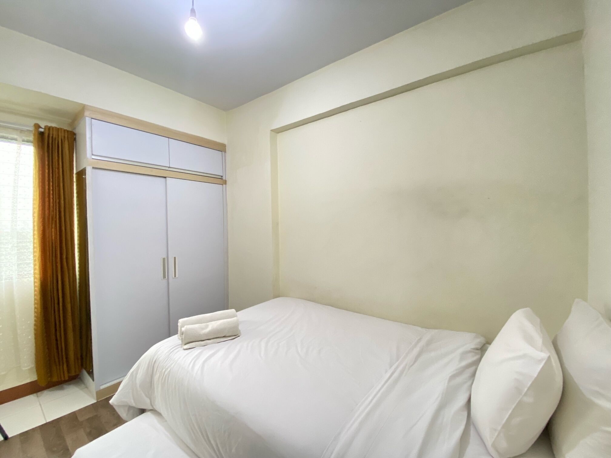 A bedroom with a bed, a wardrobe, and a window with curtains.