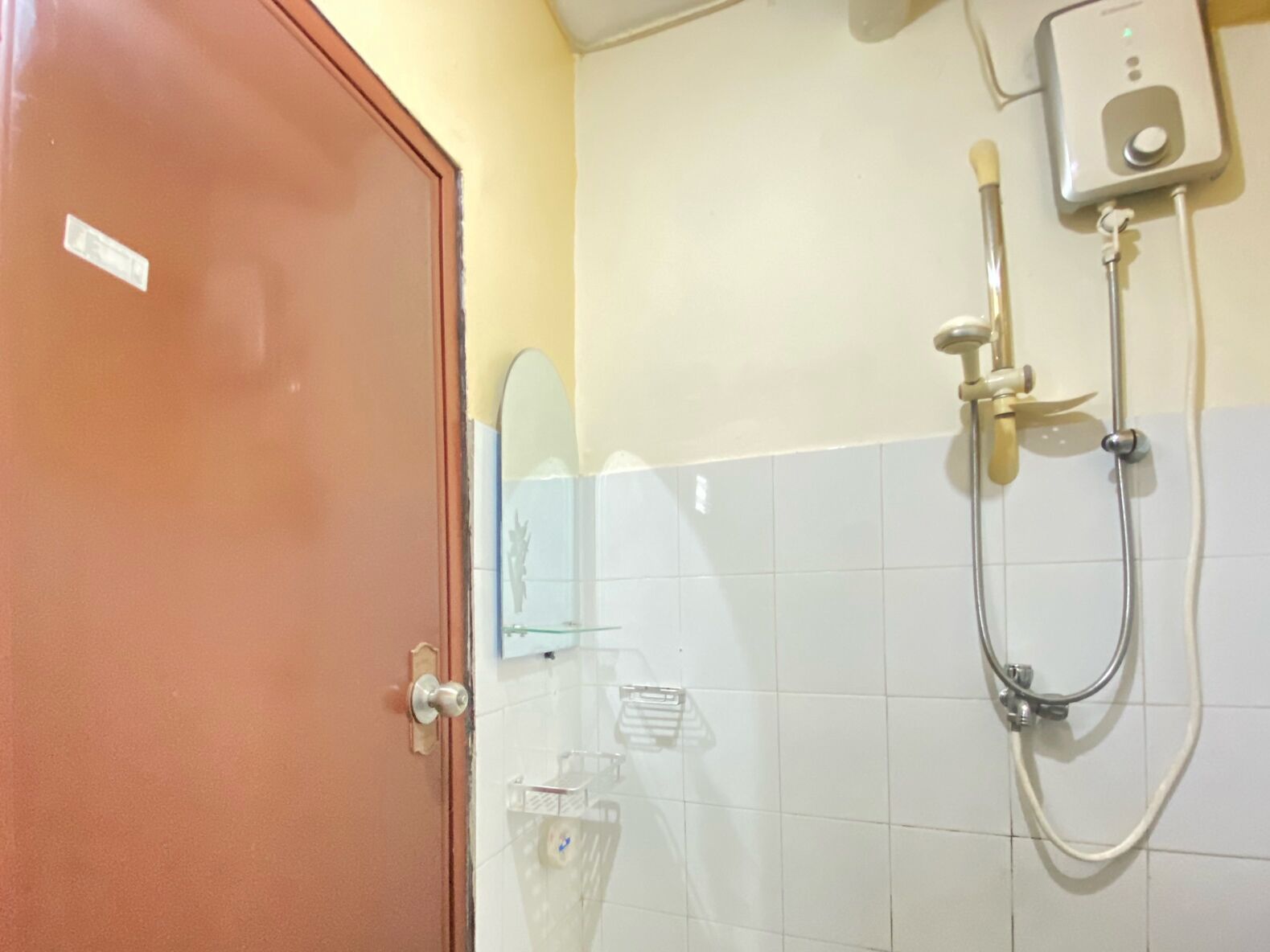 A bathroom with a shower, a towel rack, and a door.