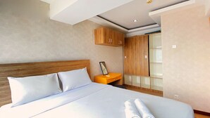 A modern hotel room with a large bed, wooden headboard, a nightstand, and a wardrobe. - Spacious And Unique 1Br At Jarrdin Cihampelas Apartment (Bandung)