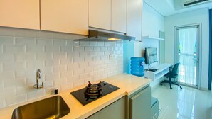 A modern kitchen with white subway tiles, stainless steel appliances, and a built-in oven. - Nice And Strategic Studio Apartment At Capitol Park Residence (Jakarta)