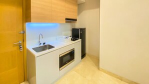 A compact kitchen with white cabinetry, a stainless steel sink, a black refrigerator, and a built-in oven. - Great Choice And Elegant 2Br At Capitol Suites Apartment (Jakarta)