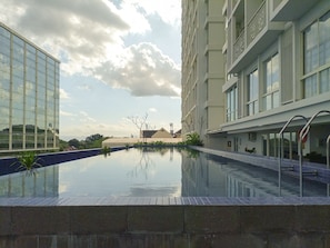 A modern hotel with a swimming pool, large windows, and a view of the surrounding landscape.