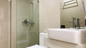 Un bagno moderno con doccia vetrata, lavandino bianco e water.